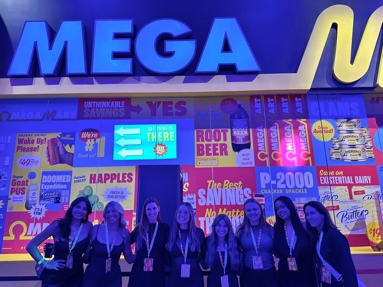 imex students and instructors pose in front of mega display 