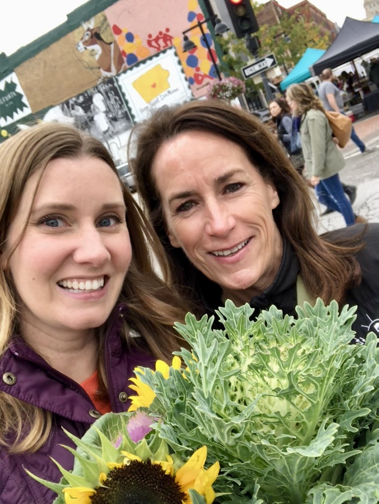 Tracy and Heather smiling for a photo with flowers