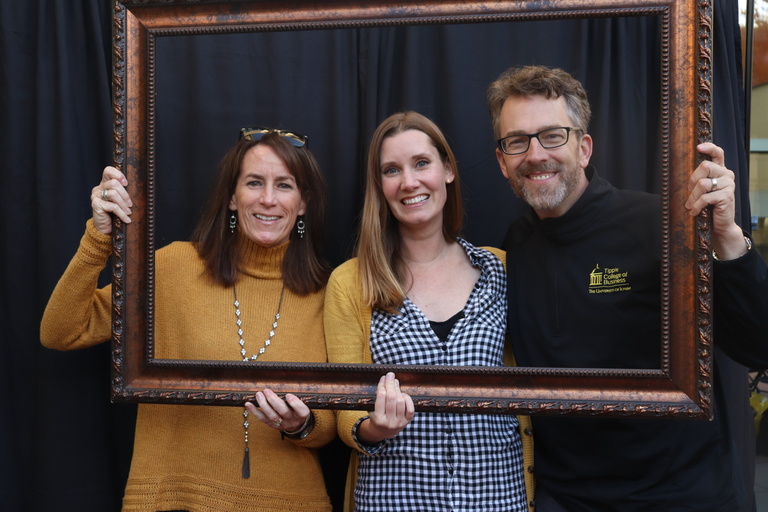 Tracy, Heather, and Ken posing for a photo with a picture frame