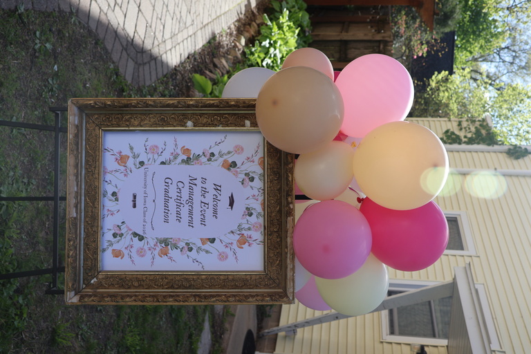Sign reading welcome to the Event Management Certificate's Spring Graduation with balloons attached