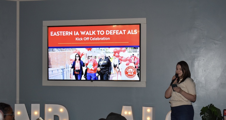 A women standing in front of a screen for the ALS association